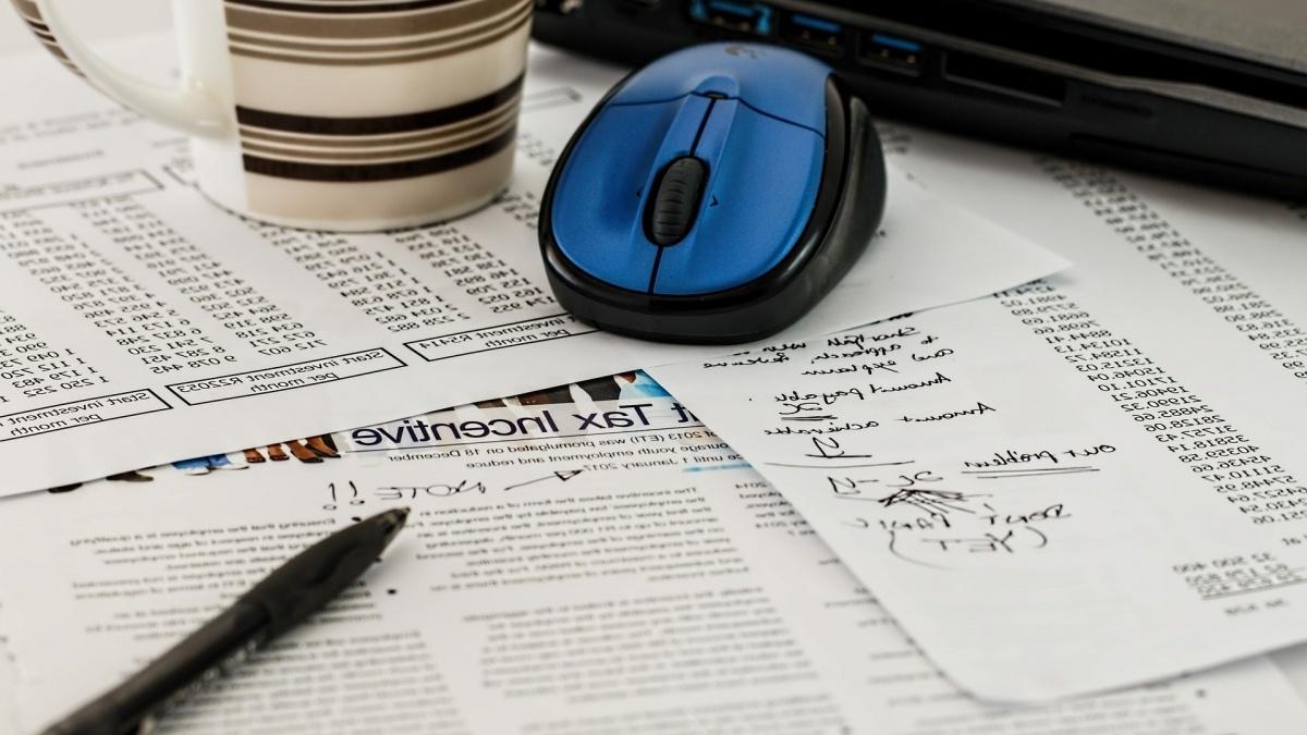 various financial forms with a pen and computer mouse on a table